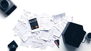 Een rommelig bureau met financiële documenten en rekenmachine.